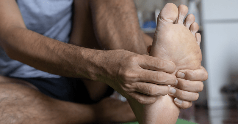 man rubbing his hand on sore feet