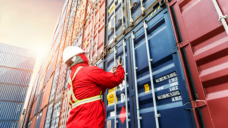Havenarbeider in veiligheidskledij die aan een container werkt